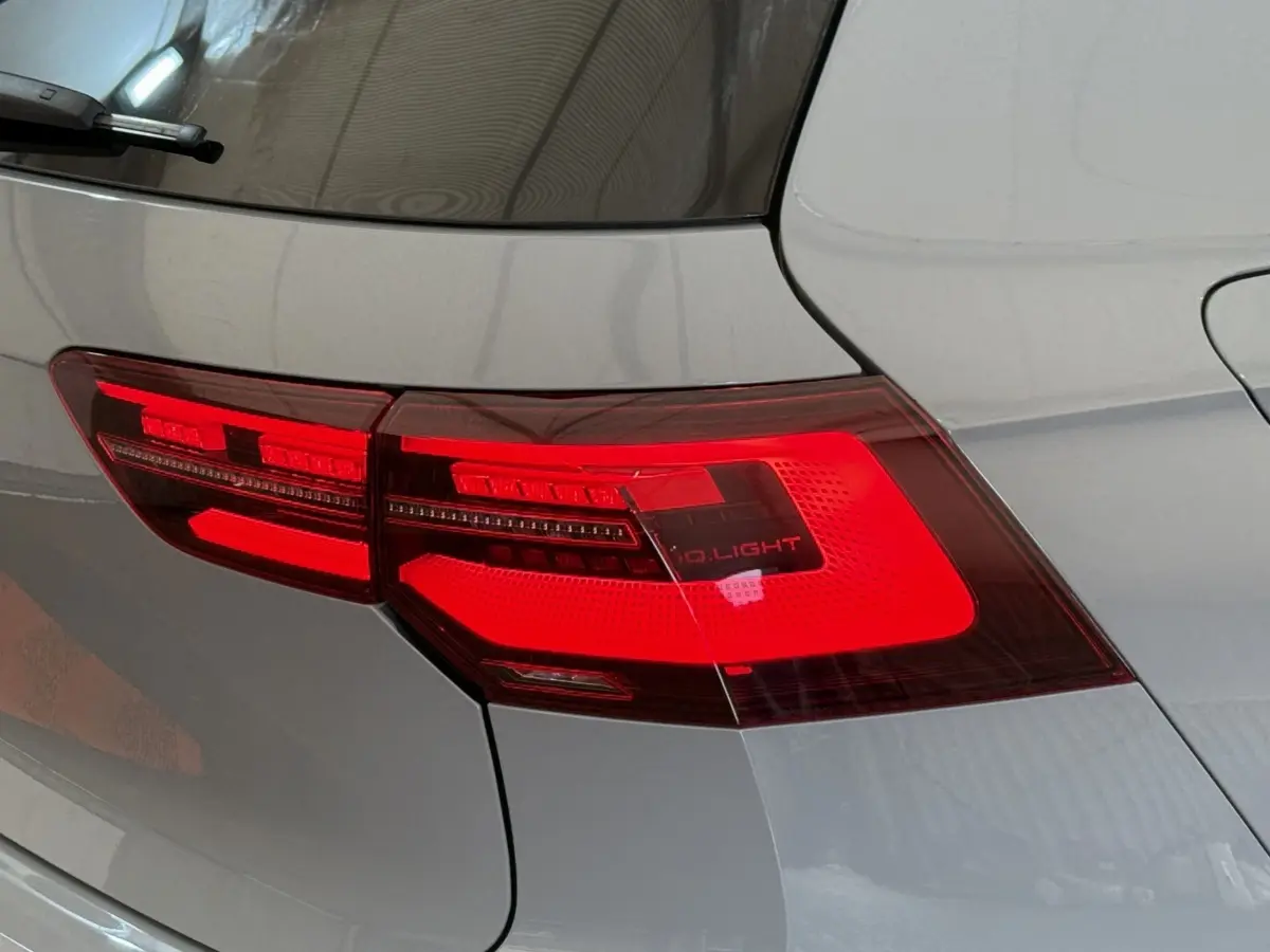 Gros plan sur le feu arrière droit rouge d’une Volkswagen Golf gris foncé, vue de l’arrière côté droit.