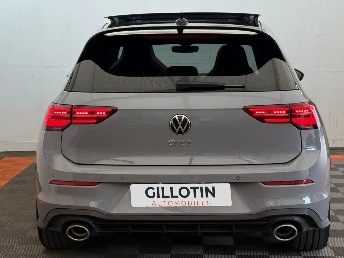 Vue arrière d'une Volkswagen Golf GTI Clubsport 2.0 TSI gris foncé avec feux LED allumés et double sortie d'échappement.