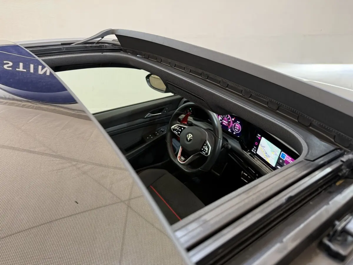 Vue intérieure côté conducteur de la Volkswagen Golf GTI Clubsport gris foncé, avec tableau de bord numérique et écran tactile.