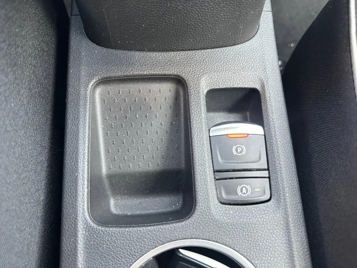 Détail de la console centrale du Renault Captur 2024 montrant les boutons du frein à main électrique et du démarrage auto, en plastique noir.
