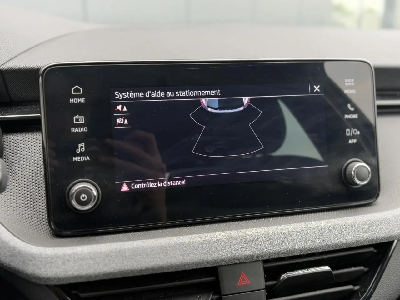 Écran tactile central du Skoda Scala 2024 affichant le système d'aide au stationnement avec commandes autour.