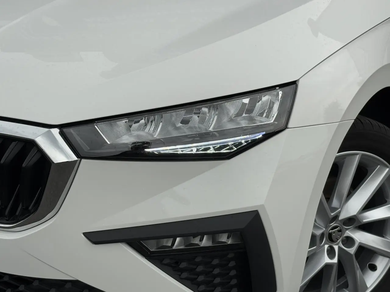 Gros plan sur l'avant droit blanc Candy d'une Skoda Scala 2024, mettant en valeur le phare et la jante alliage 17 pouces.