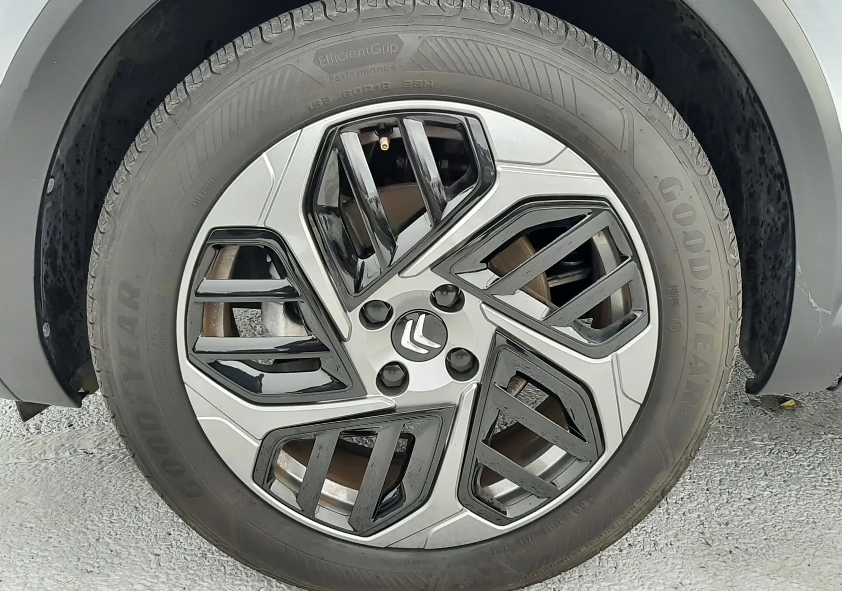 Gros plan sur la roue avant droite d'une Citroën C4 gris acier 2024 avec jante alliage au design géométrique bicolore.