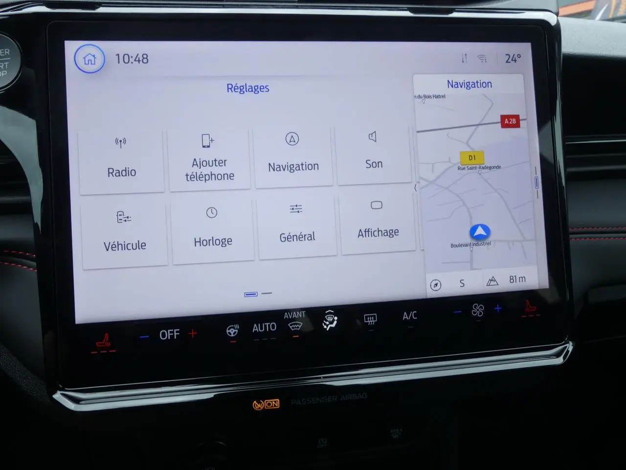 Écran tactile SYNC 4 de la Ford Puma 2025 montrant les réglages et la navigation, avec surpiqûres rouges visibles.