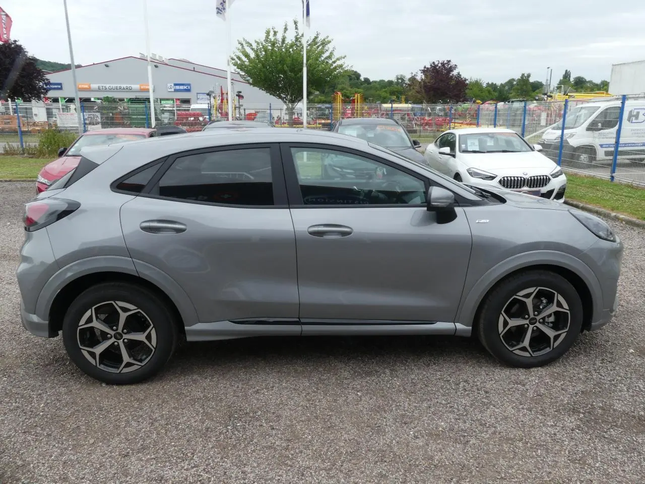 Ford Puma 2025 gris métallisé vu de profil côté gauche avec jantes alliage et vitres arrière surteintées.