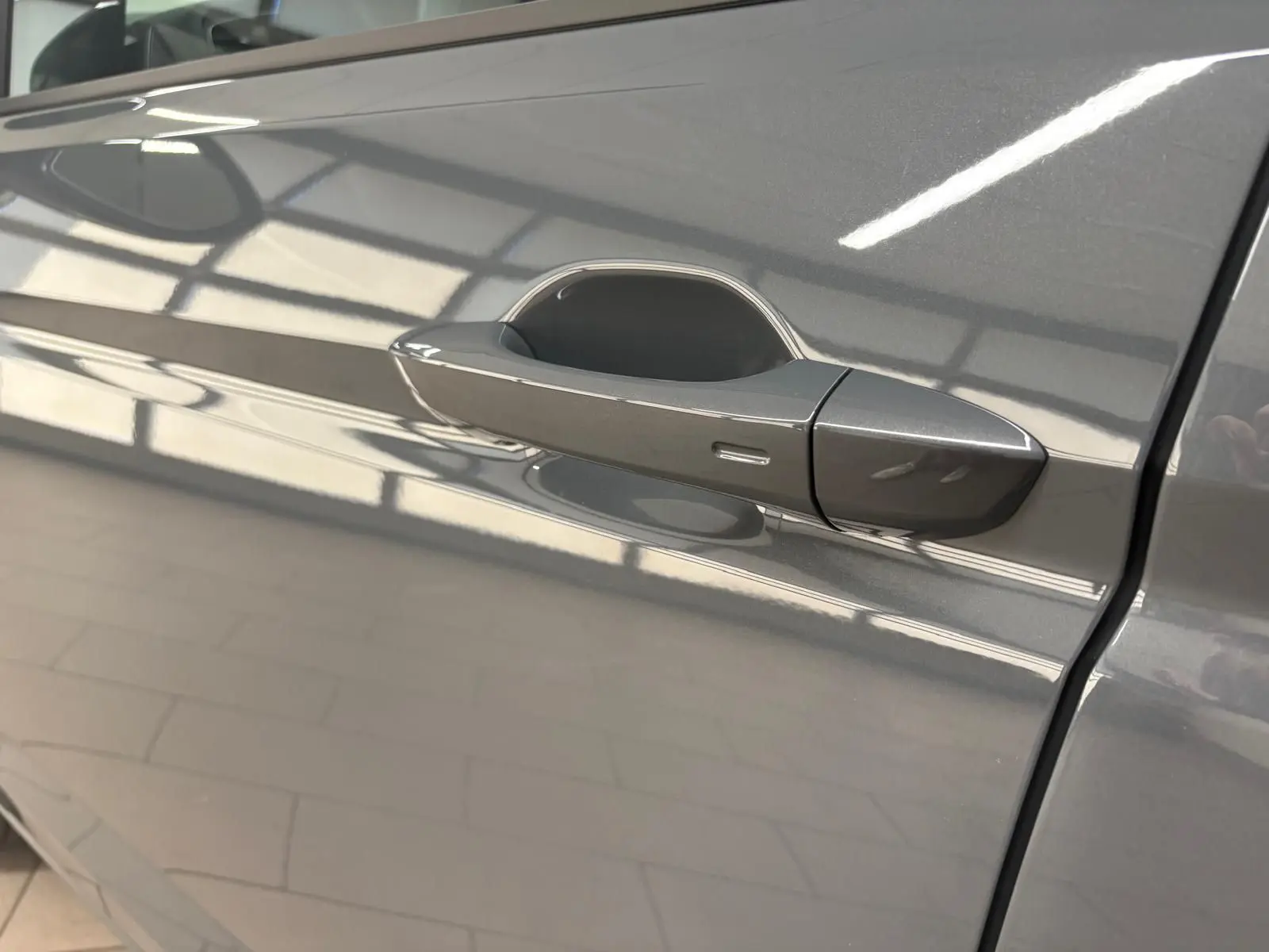 Poignée de porte côté gauche du Volkswagen Touran gris dauphin 2025, finition VW Edition avec peinture métallisée.
