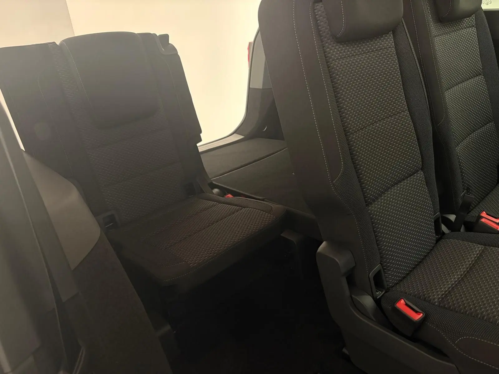 Vue intérieure sur les sièges arrière noirs du Volkswagen Touran 2025, mettant en valeur la troisième rangée rabattable.