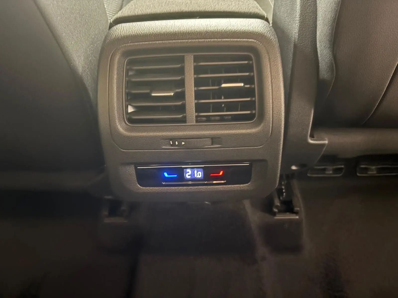 Gros plan sur la ventilation arrière et le réglage numérique de la climatisation à 21°C dans un Volkswagen Touran gris Dauphin.