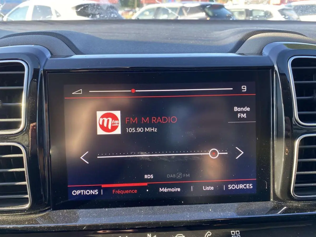 Écran tactile central du tableau de bord du Citroën C5 Aircross blanc, affichant la radio FM sur 105,90 MHz.
