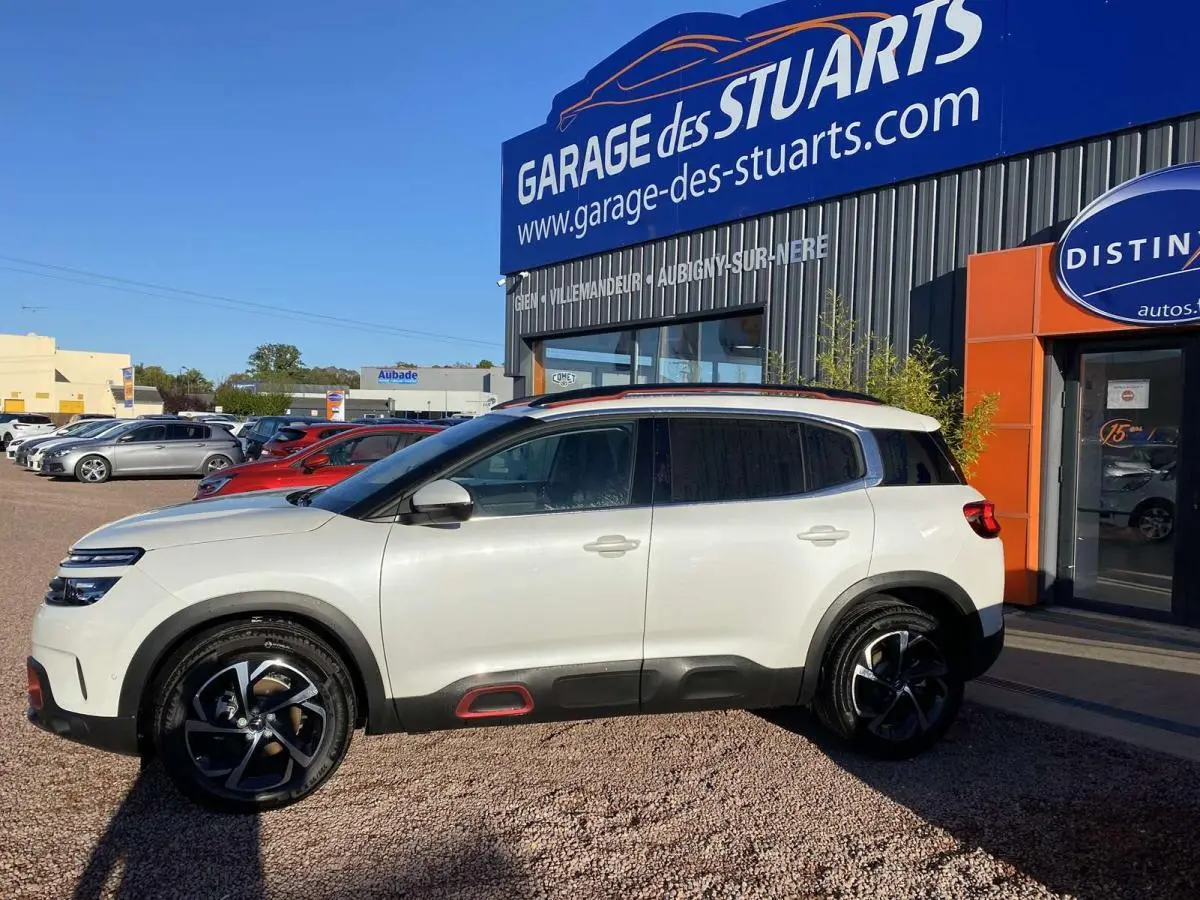 Vue de profil côté gauche d'un Citroën C5 Aircross blanc nacré avec inserts Deep Red et jantes bi-ton 18 pouces.