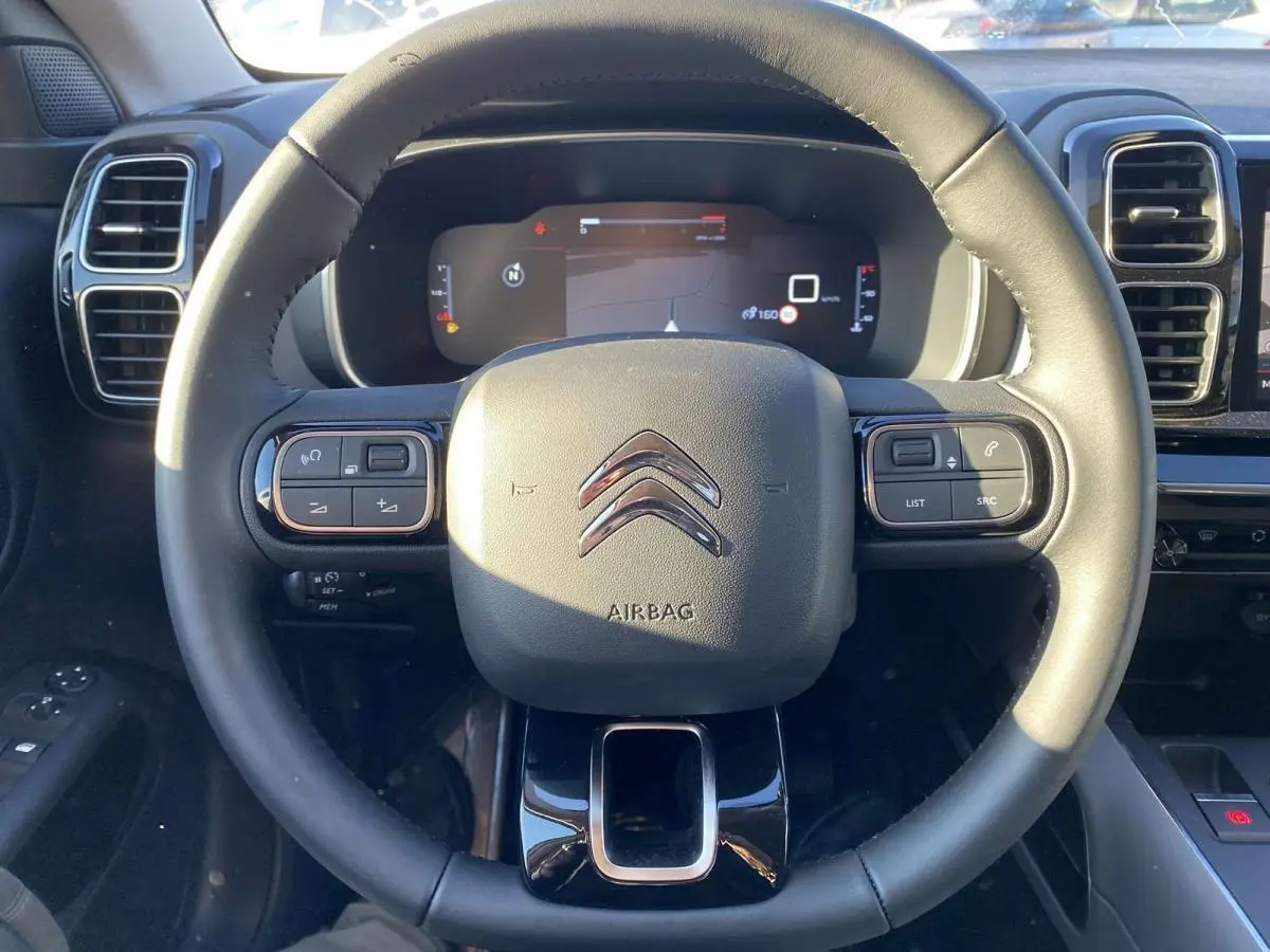Vue rapprochée du volant en cuir noir du Citroën C5 Aircross 2021 avec commandes intégrées et tableau de bord numérique.