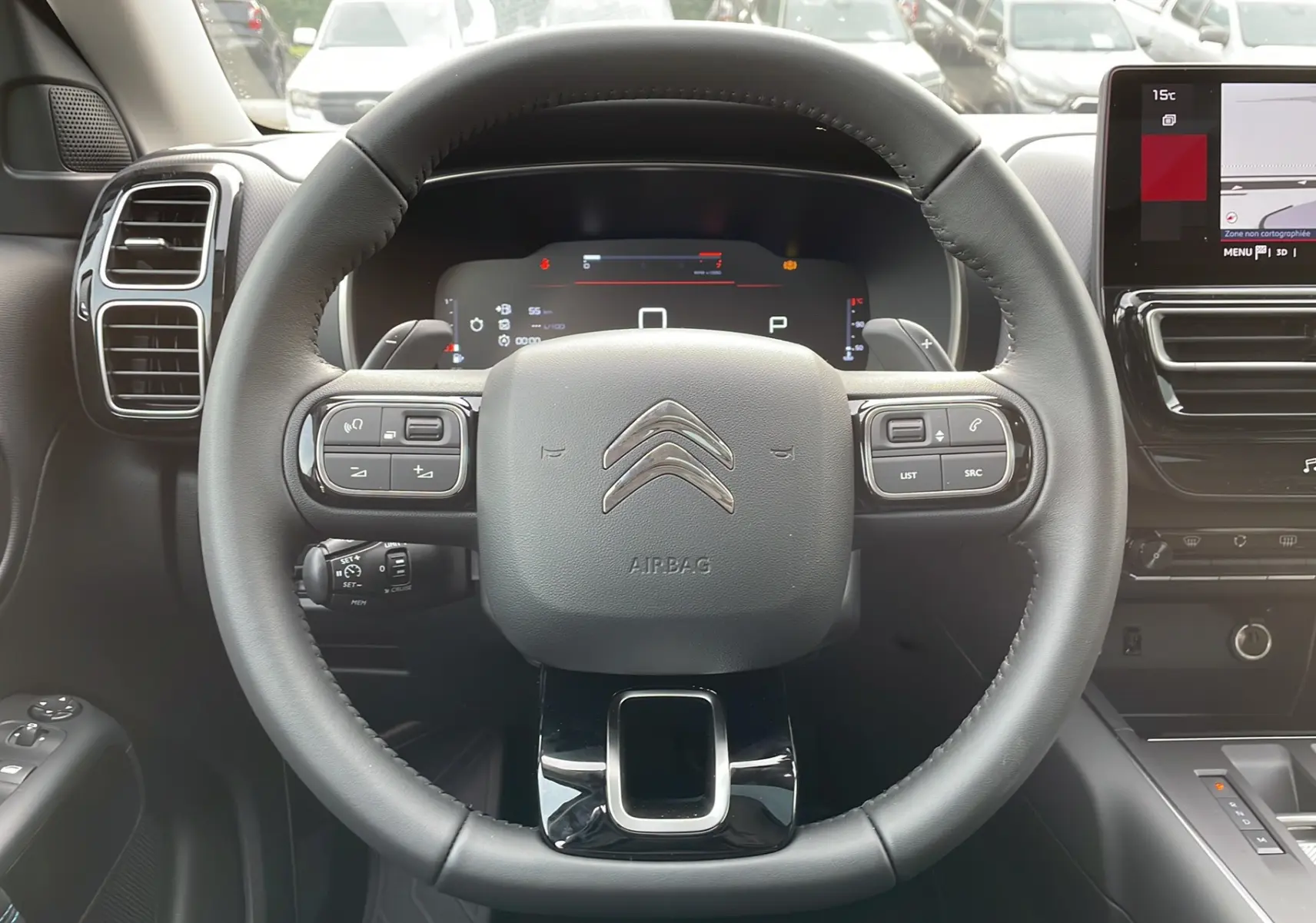 Vue rapprochée du volant noir du Citroën C5 Aircross Hybrid 2025 avec commandes intégrées et tableau de bord numérique.