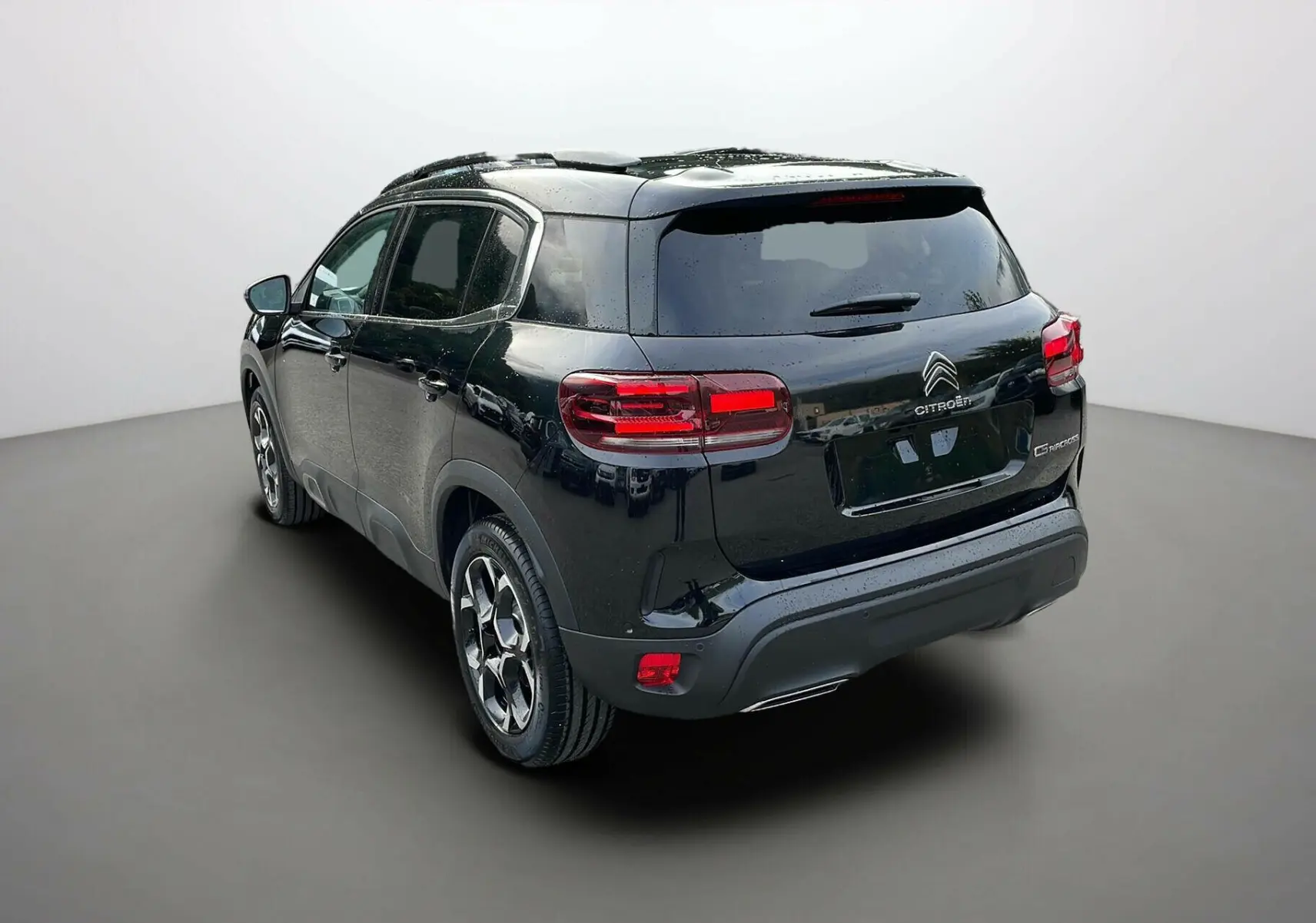 Vue 3/4 arrière droite d'un Citroën C5 Aircross noir 2025 avec feux arrière LED et toit panoramique.