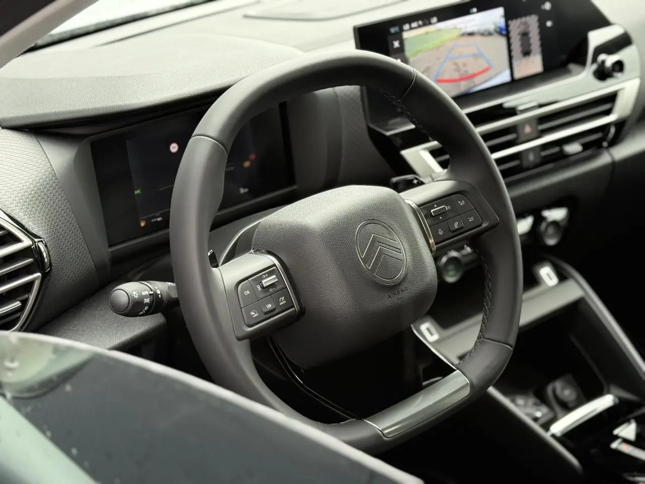 Volant cuir noir avec commandes intégrées dans l'habitacle moderne de la Citroën C4 hybride 2025, vue côté conducteur.