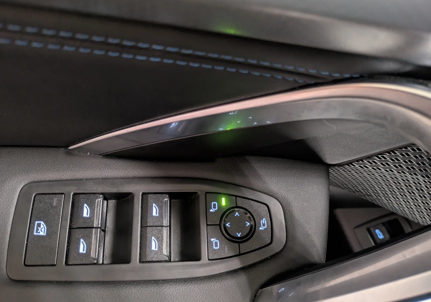 Gros plan sur les commandes des vitres électriques et rétroviseurs du côté gauche intérieur d'un BMW X1 blanc 2025.