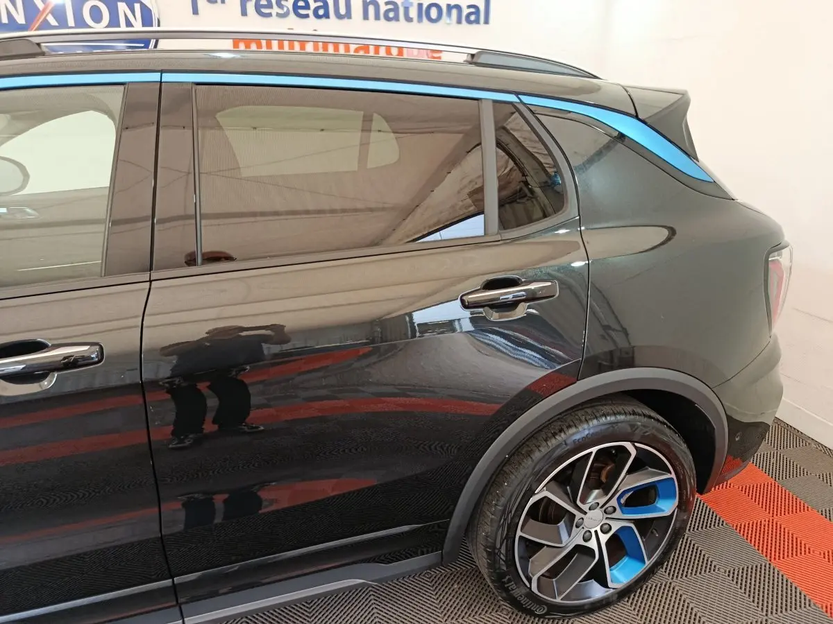 Vue côté droit arrière du SUV Link & Co 01 noir avec jantes noires et bleues et bande bleue sur le toit.