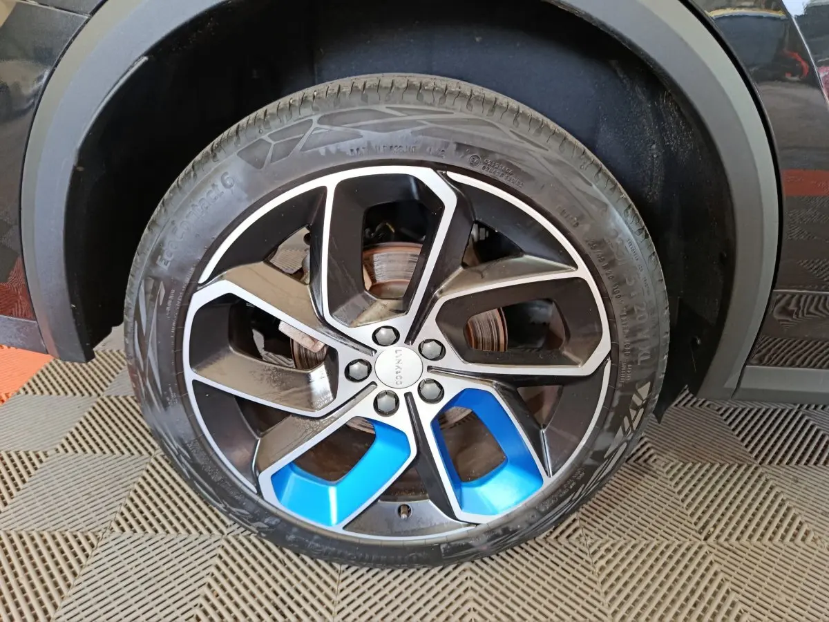 Gros plan sur la roue avant droite noire et bleu métallisé du SUV LINK & CO 01 hybride rechargeable 2023.