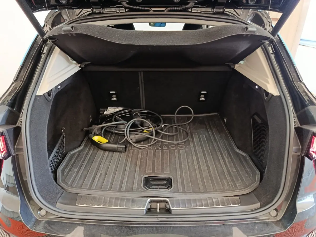 Coffre ouvert d’un SUV Link & Co 01 noir, vue arrière, avec câble de recharge hybride visible au sol.