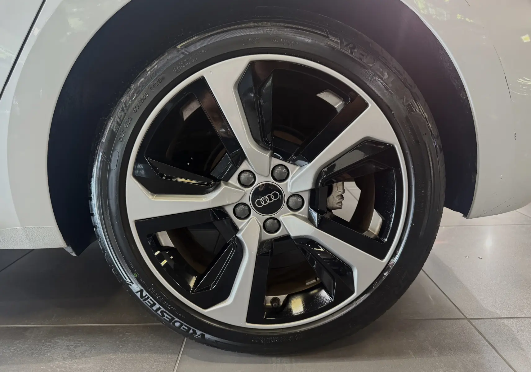 Gros plan sur la jante avant droite bicolore noire et argentée d'une Audi A1 blanche toit noir 2024 S-Line.