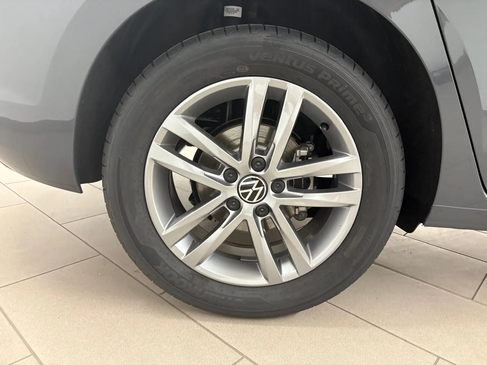 Gros plan sur la roue arrière droite gris dauphin du Volkswagen Touran 2025 avec jante alliage 17 pouces et logo VW central.