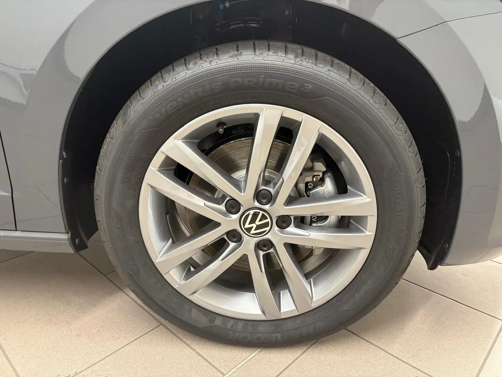 Gros plan sur la roue avant droite gris dauphin du Volkswagen Touran 2025 avec jante alliage 17 pouces et logo VW central.