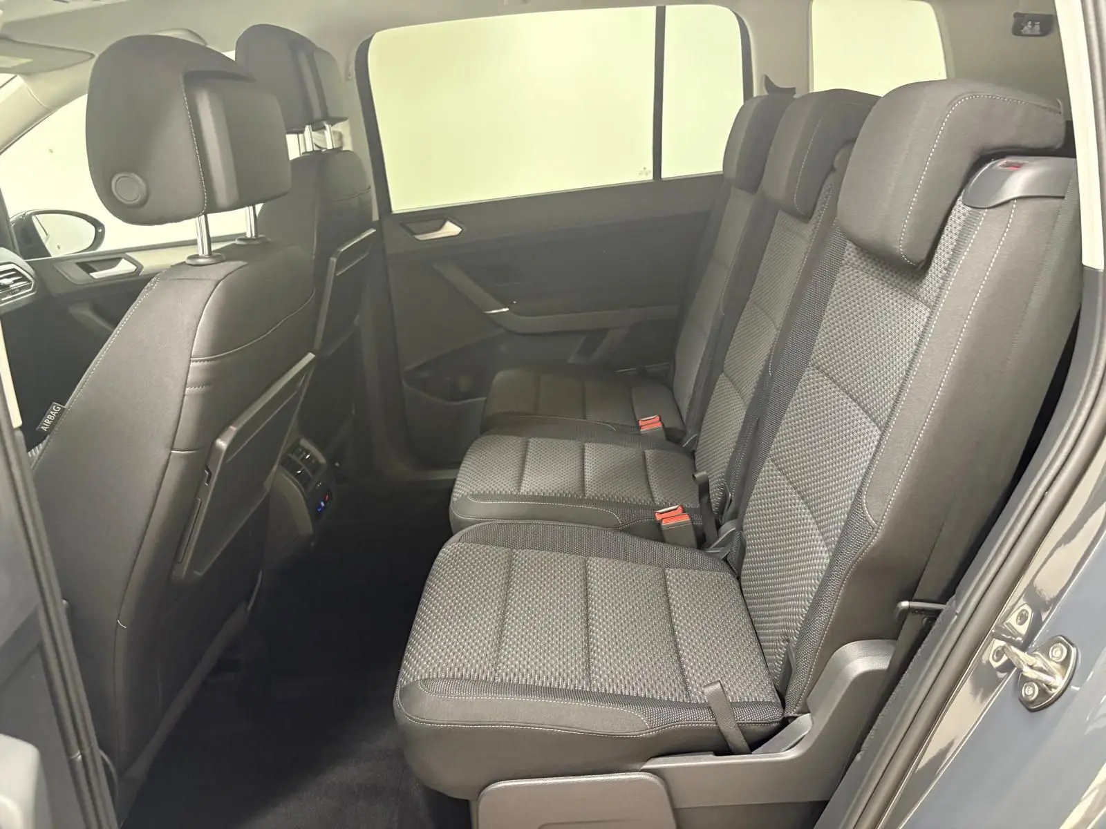 Vue latérale intérieure des sièges arrière gris foncé du Volkswagen Touran 2025, version 7 places avec finition VW Edition.