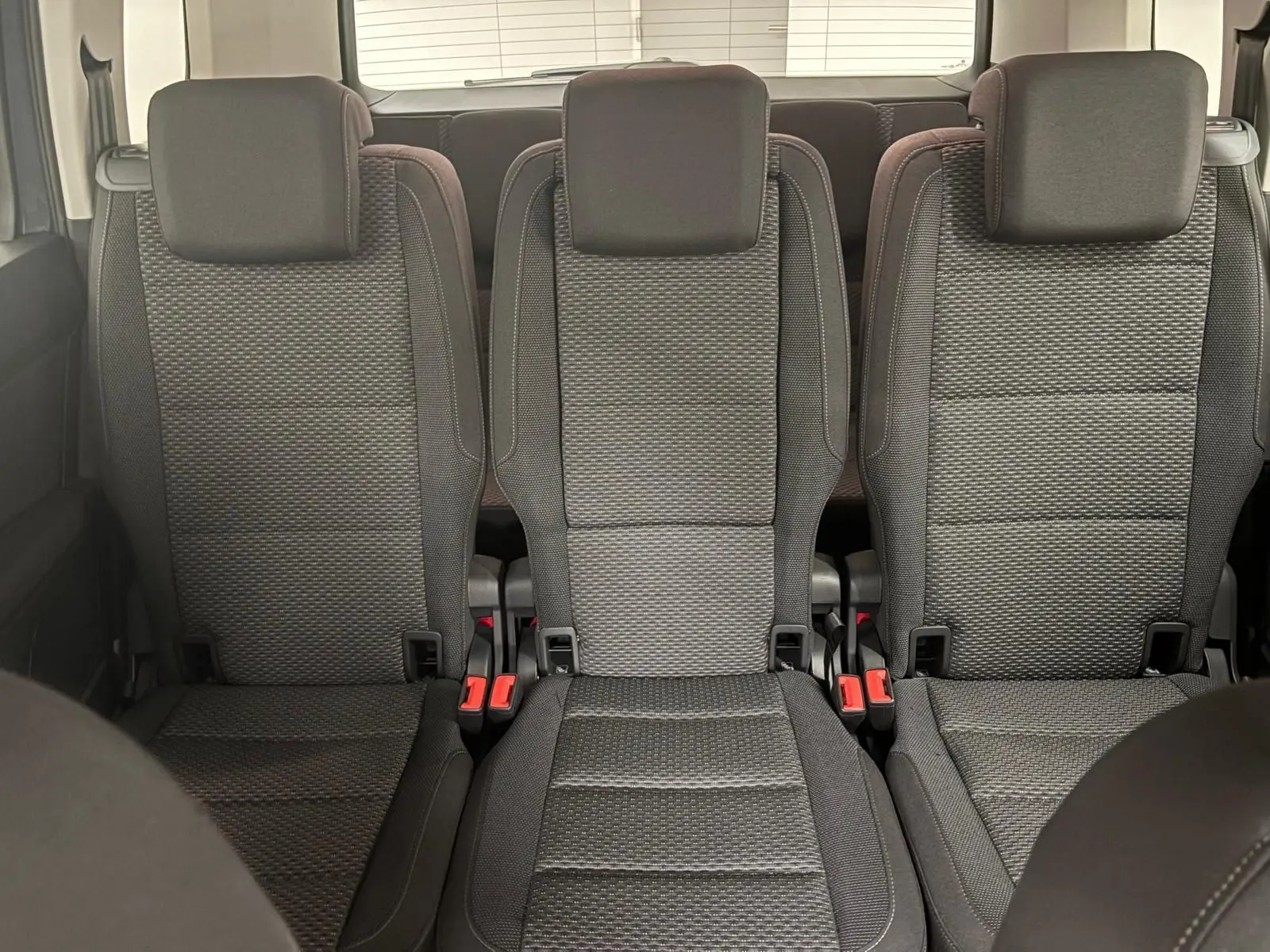 Vue intérieure centrée sur les trois sièges arrière en tissu gris du Volkswagen Touran 2025, version 7 places.