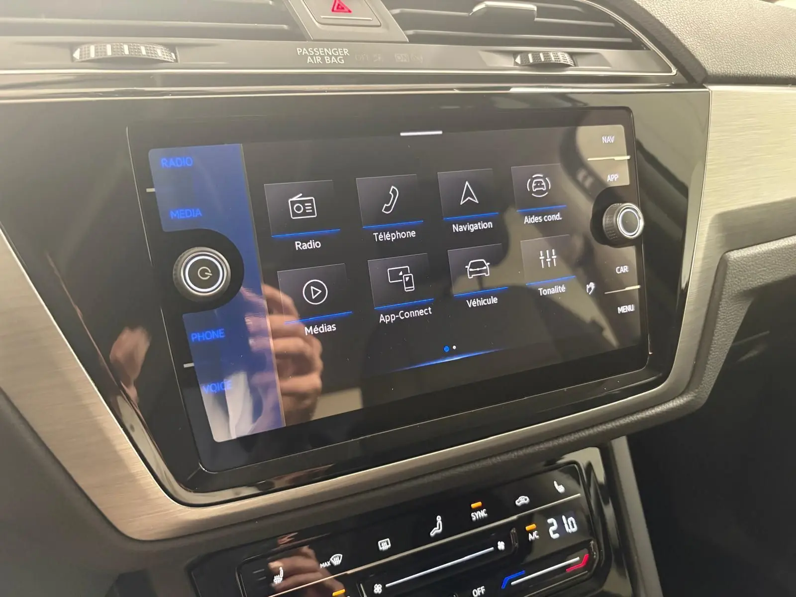 Écran tactile central du Volkswagen Touran 2025 gris dauphin, affichant les options multimédia et aides à la conduite.