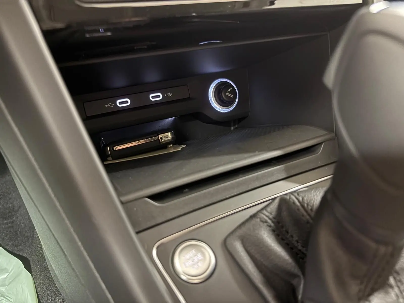 Détail de la console centrale du Volkswagen Touran 2025 avec ports USB, allume-cigare illuminé et bouton start/stop.
