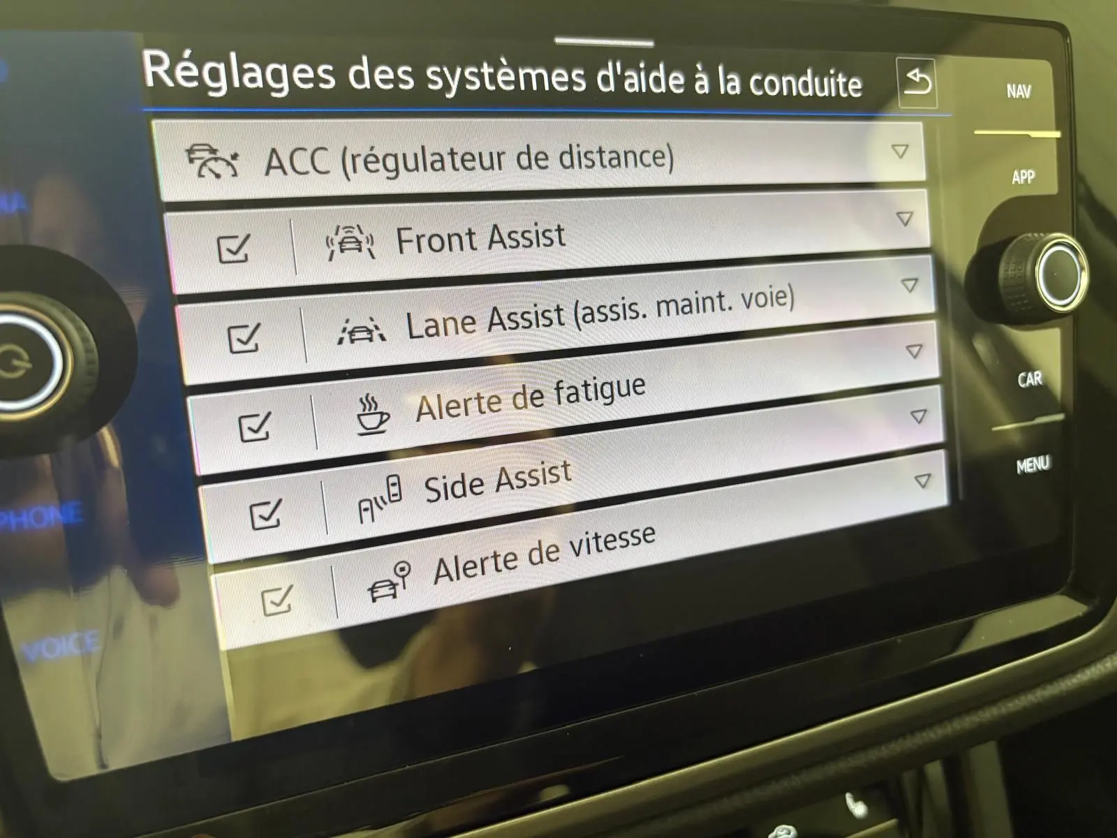 Écran tactile du Volkswagen Touran 2025 affichant les réglages des aides à la conduite avec options activées.