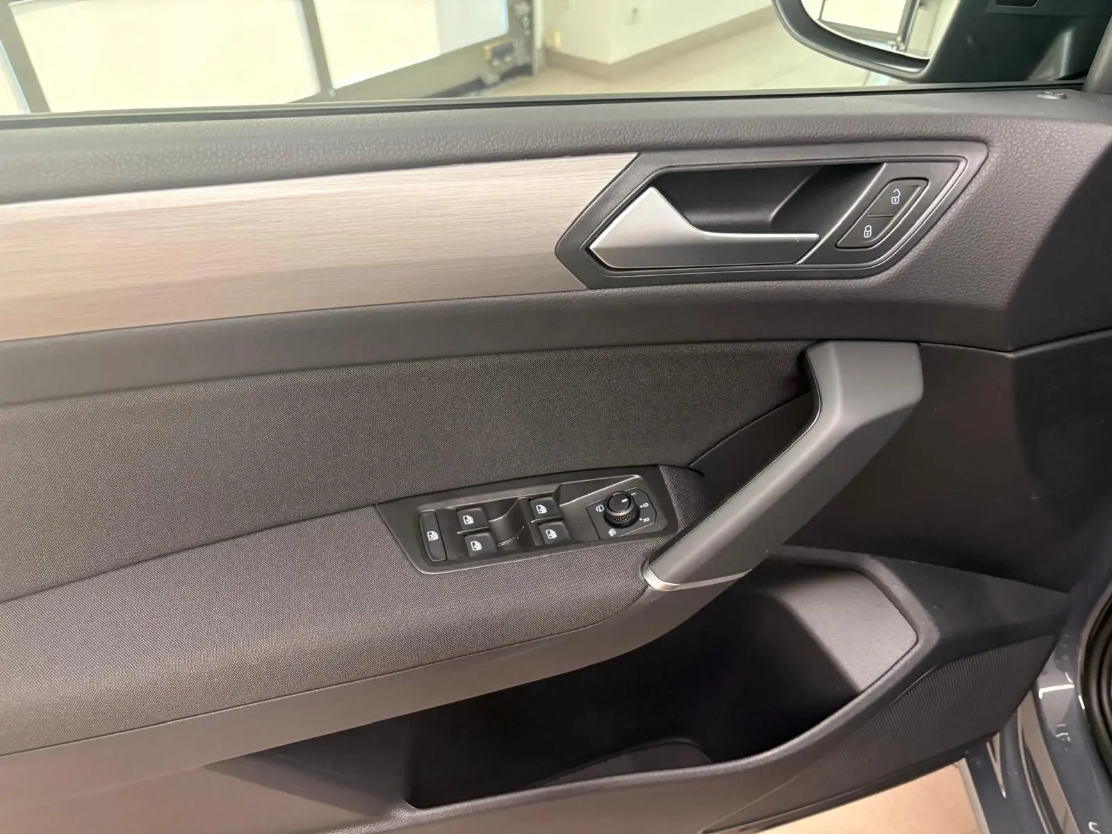 Intérieur côté gauche de la porte d'un Volkswagen Touran gris Dauphin 2025, avec commandes de vitres et verrouillage.