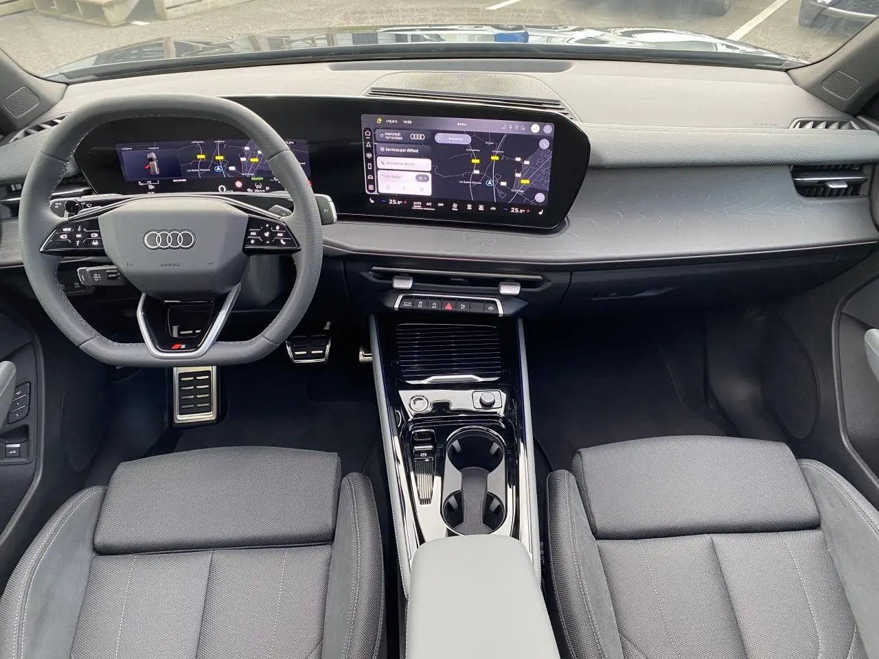 Vue intérieure avant de l'Audi Q3 2025, tableau de bord moderne noir avec écran tactile et volant sport multifonction.