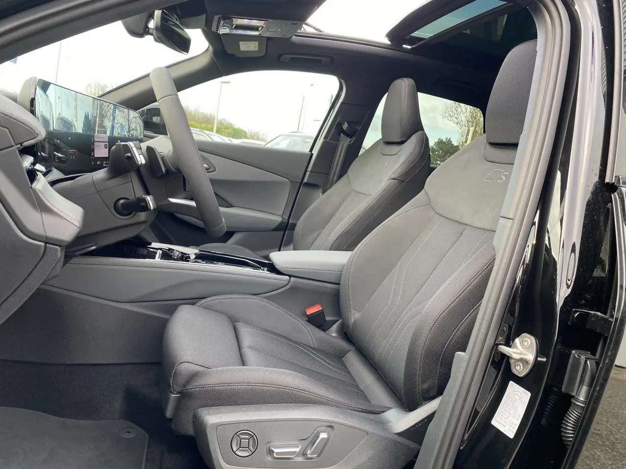 Intérieur côté conducteur d'un Audi Q3 noir mythic, sièges sport S line en tissu gris avec surpiqûres et toit panoramique.