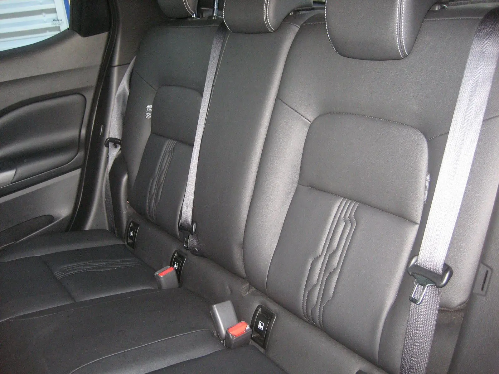 Vue intérieure montrant la banquette arrière en cuir noir avec ceinture grise du Nissan Juke 1.6 Hybrid 2024.