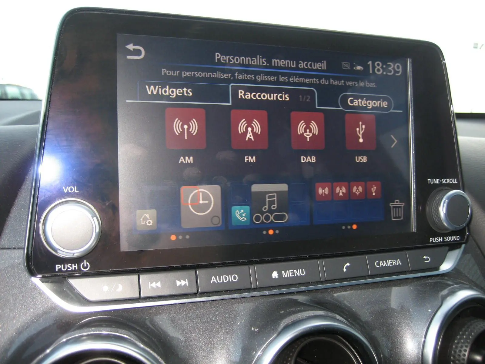Écran tactile central du Nissan Juke 1.6 Hybrid 143 Tekna 2024, affichant le menu de personnalisation des raccourcis audio.
