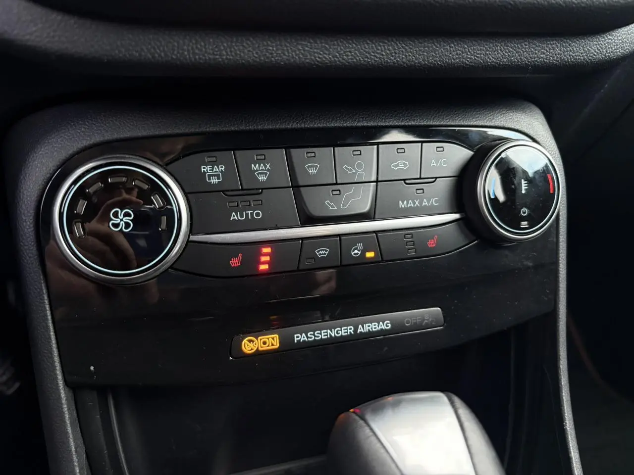 Gros plan sur la console centrale noire du Ford Puma 2023, montrant les commandes de climatisation et sièges chauffants activés.