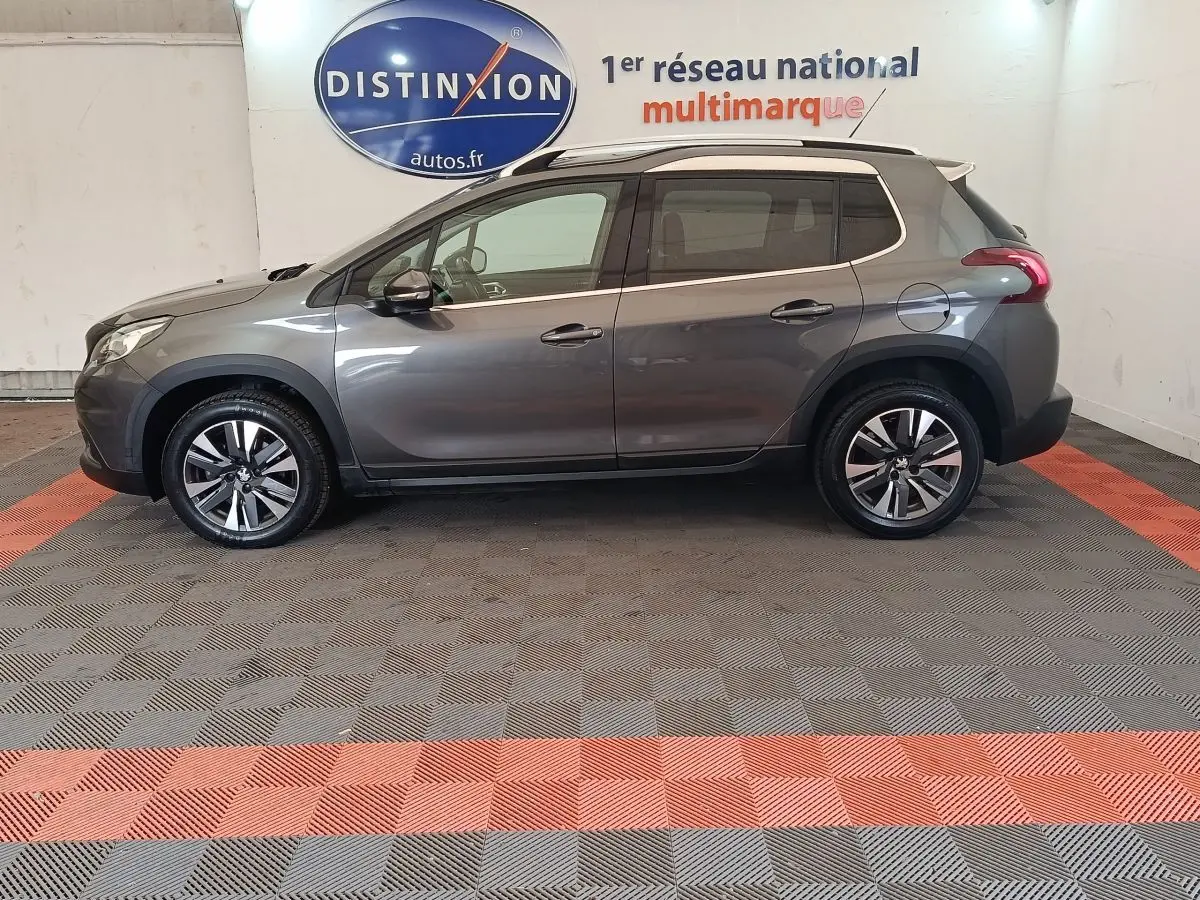 Profil droit d'un Peugeot 2008 gris foncé de 2019, version Puretech Allure, avec jantes alliage et toit blanc contrasté.