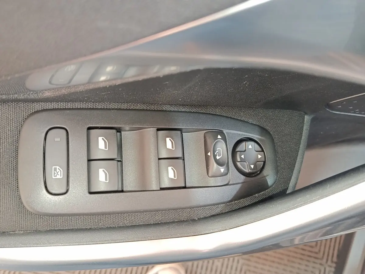 Gros plan sur les commandes des vitres et rétroviseurs côté conducteur d'une Peugeot 2008 gris foncé, version 2019.