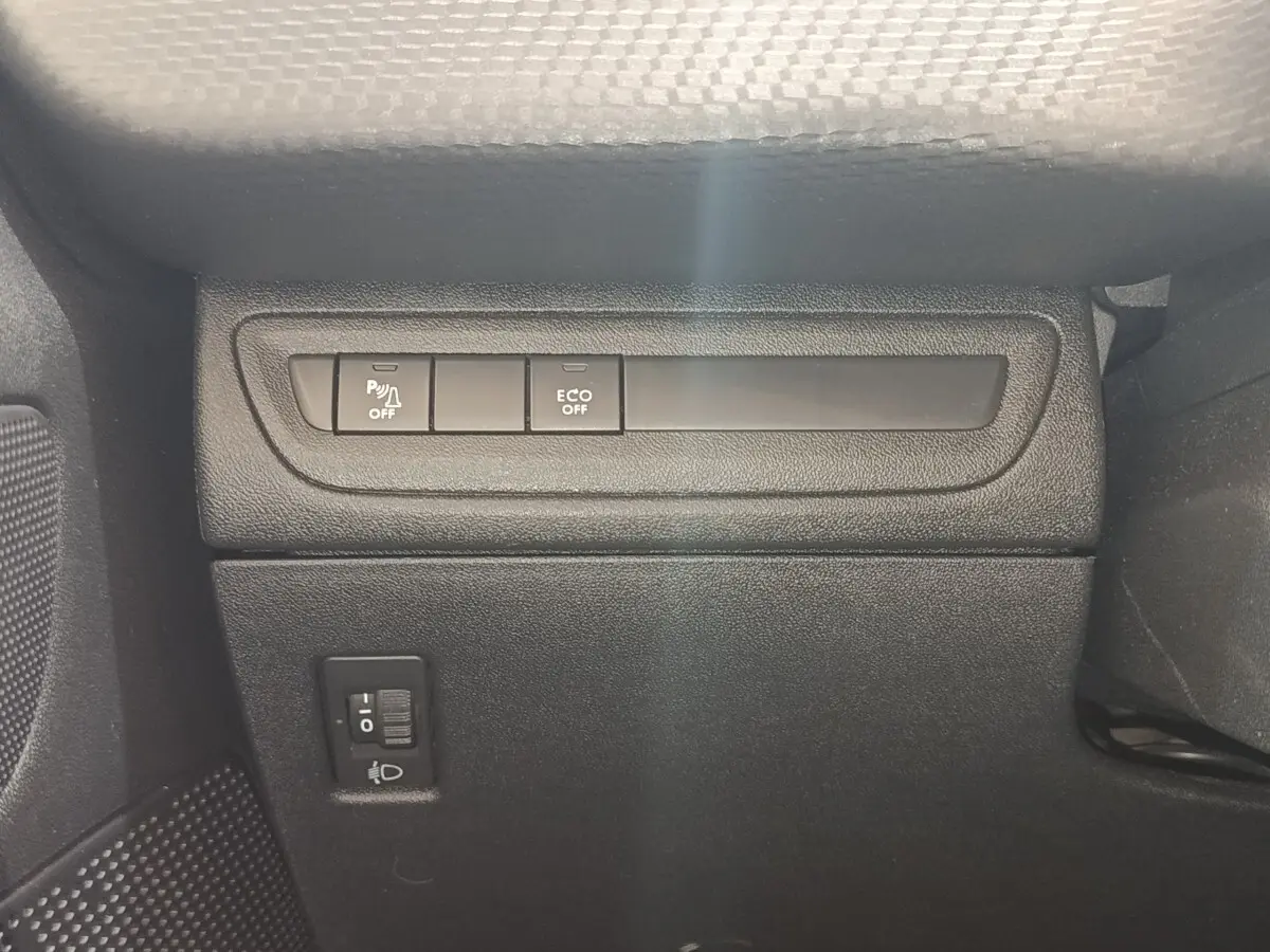 Gros plan sur les commandes de désactivation du parking assisté et mode ECO, côté gauche intérieur d’un Peugeot 2008 gris foncé.
