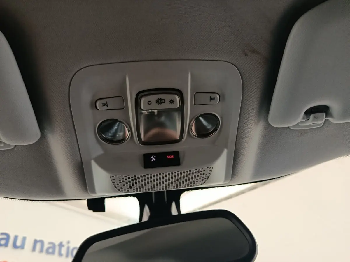 Vue intérieure en contre-plongée du plafonnier gris clair avec commandes d’éclairage et bouton SOS du Peugeot 2008 gris foncé.