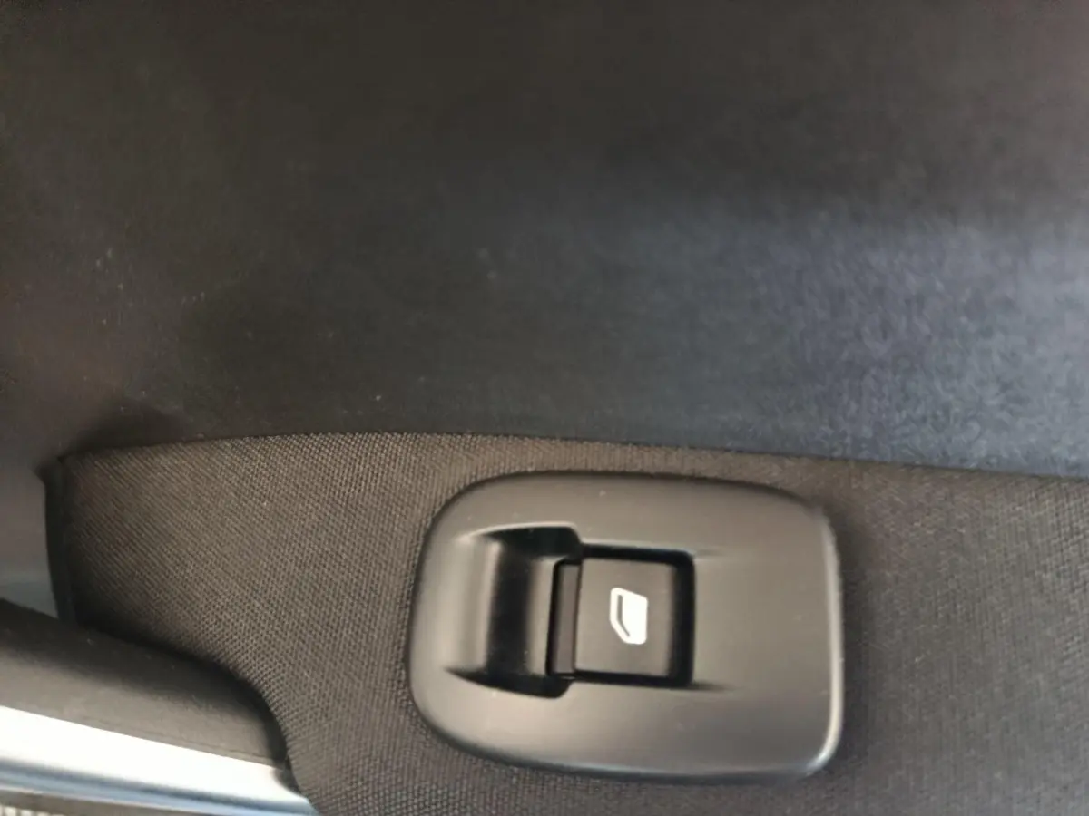 Gros plan sur le bouton de commande de lève-vitre côté conducteur d’un Peugeot 2008 gris foncé.