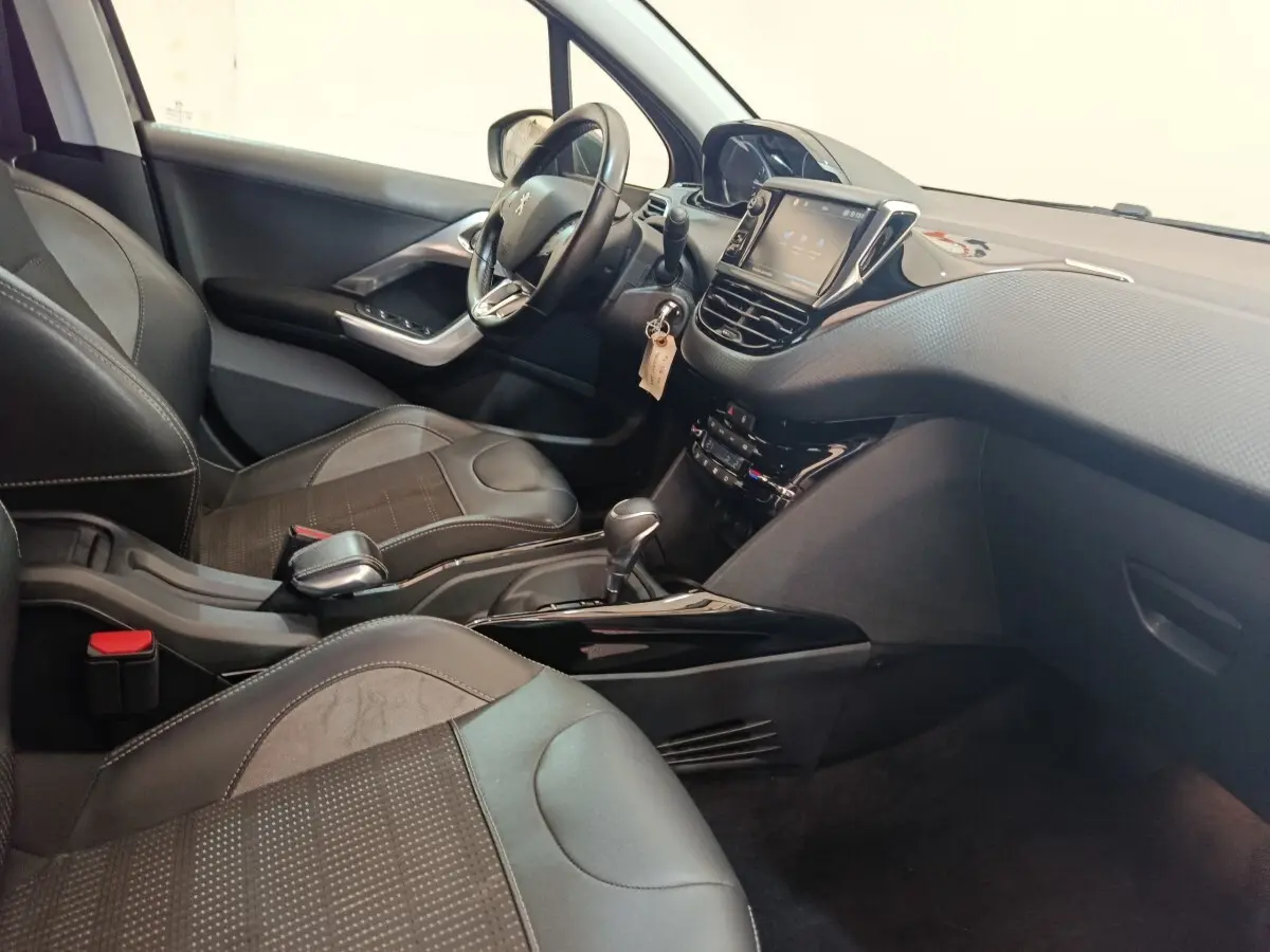 Vue intérieure côté conducteur du Peugeot 2008 gris foncé, avec tableau de bord tactile et volant cuir multifonctions.
