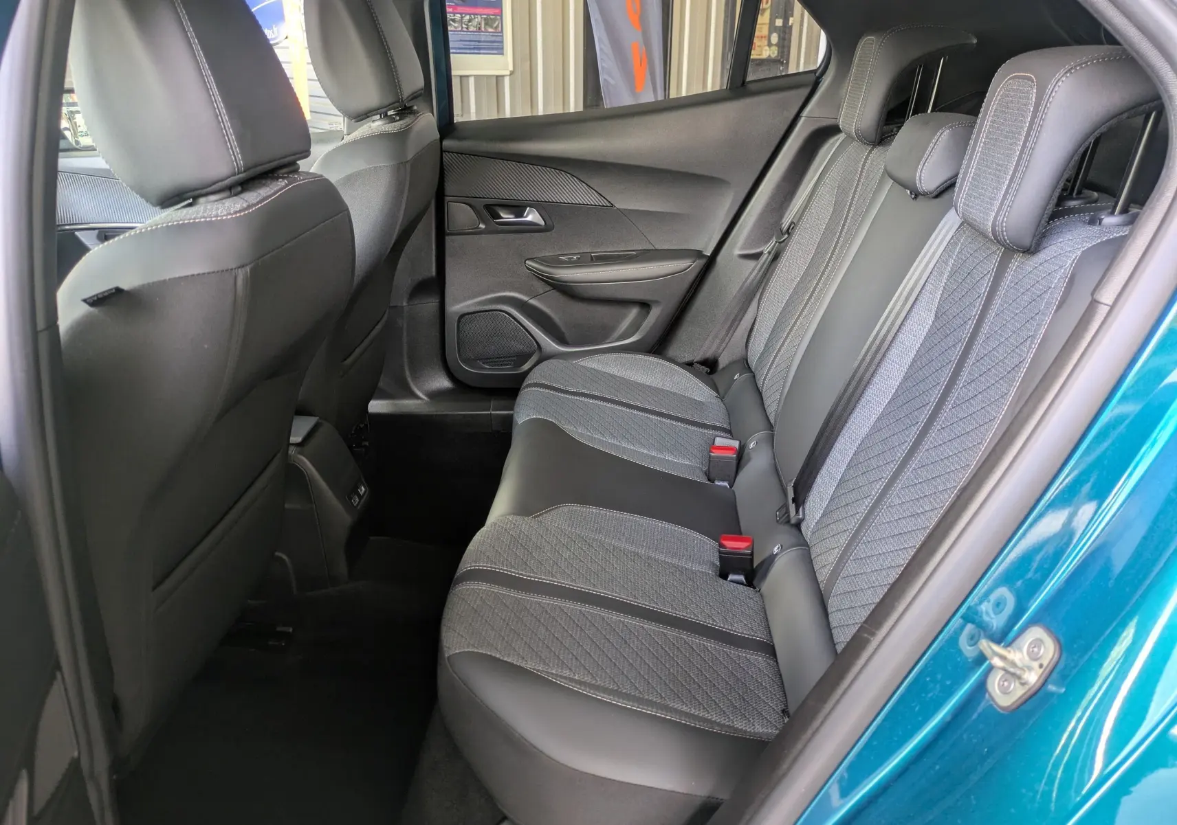 Vue intérieure arrière côté droit du Peugeot 2008 Hybrid 145 bleu obsession, sellerie tissu et cuir gris avec surpiqûres contrastées.