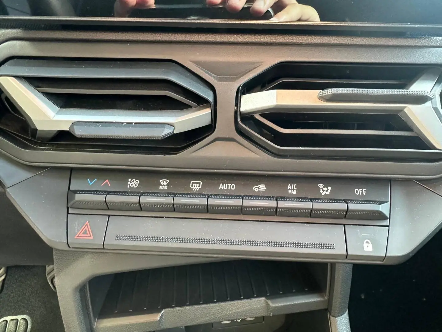 Vue rapprochée de la console centrale du Dacia Duster 2025, boutons de climatisation et aérateurs noirs.