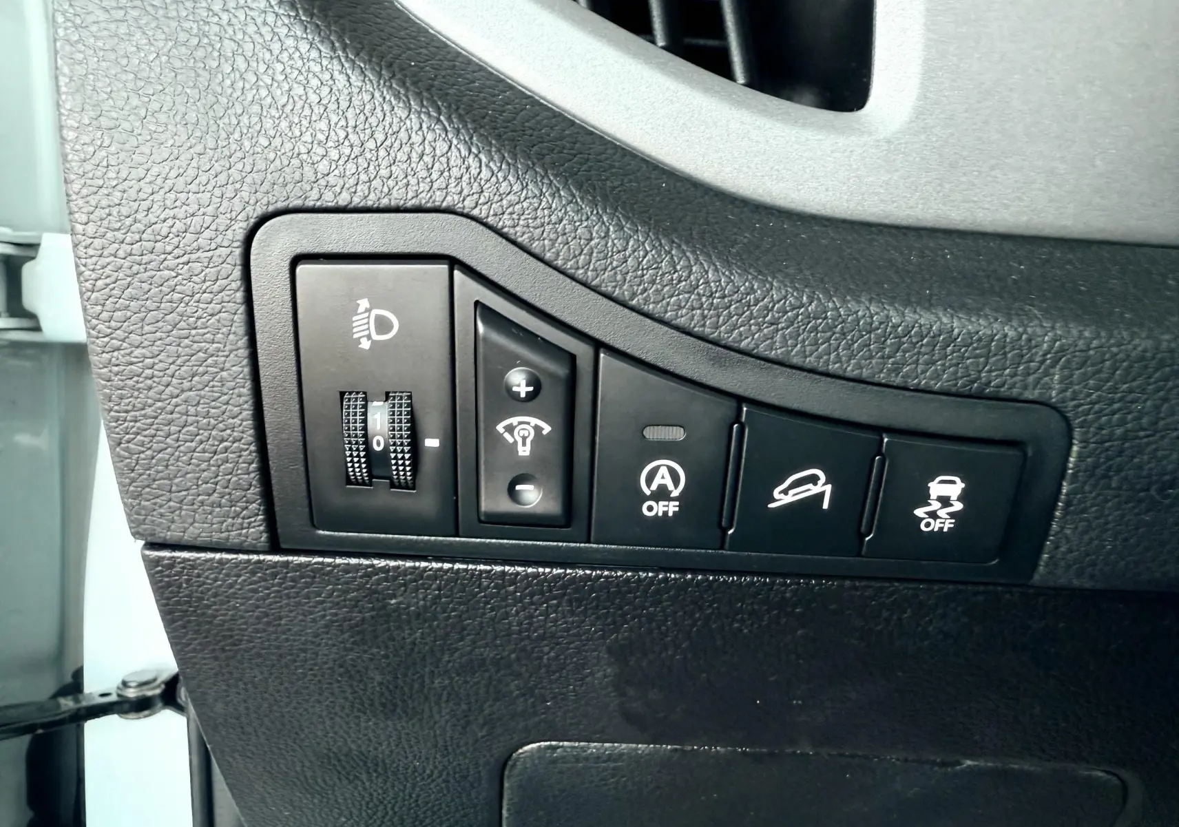 Gros plan sur les commandes de réglage d'éclairage et d'assistance du tableau de bord d'un Kia Sportage blanc.
