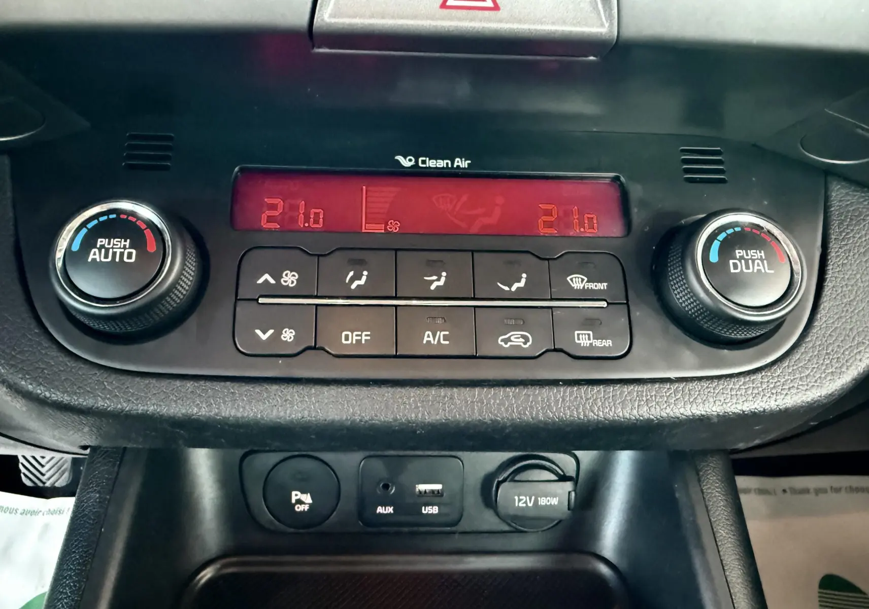 Vue rapprochée du tableau de bord du Kia Sportage 2015 montrant la climatisation automatique avec affichage digital rouge.