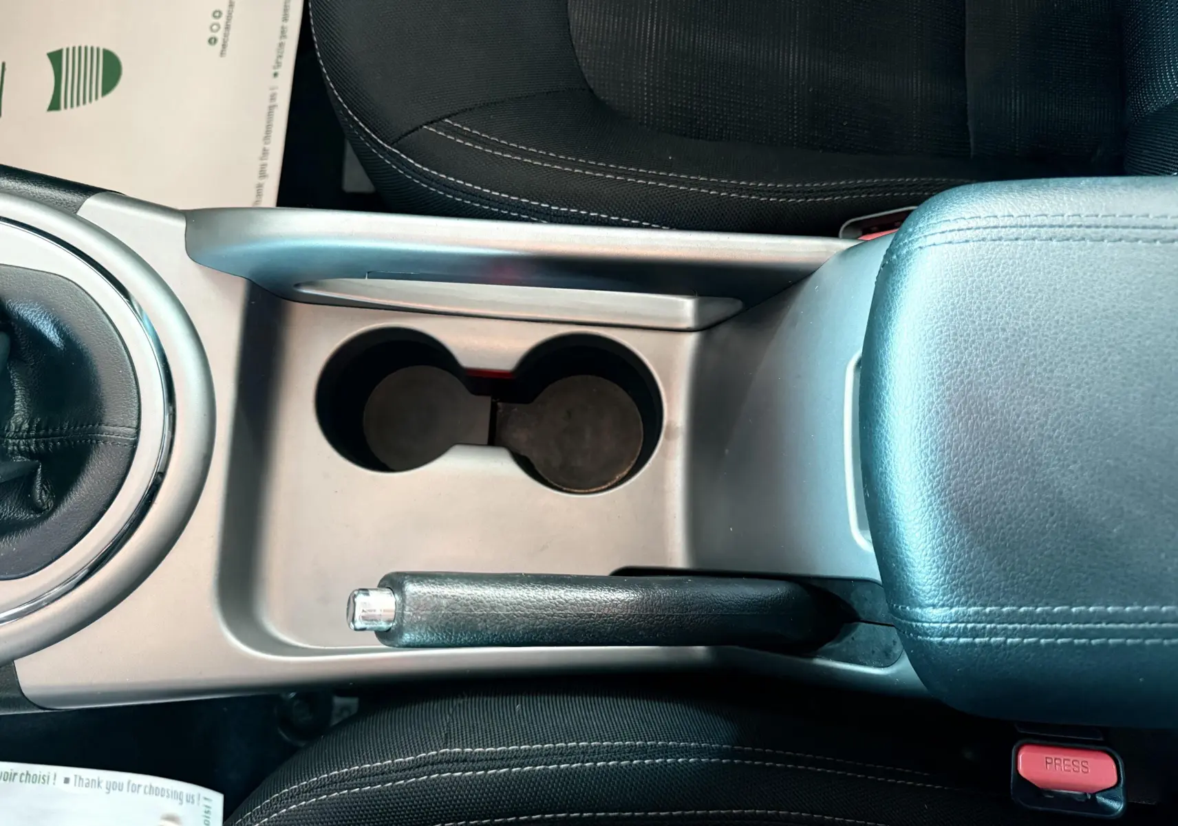 Vue plongeante sur la console centrale noire et grise avec frein à main et porte-gobelets du Kia Sportage blanc 2015