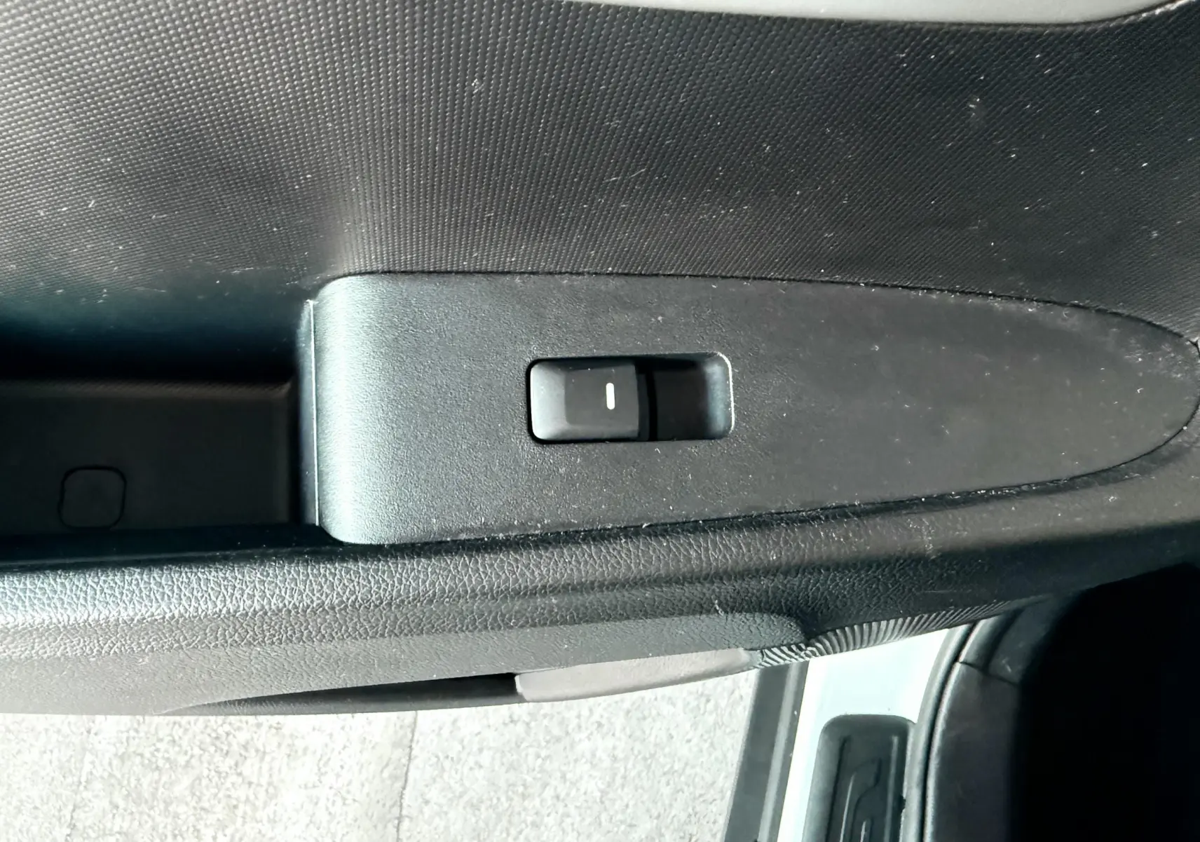 Bouton de commande de vitre sur la portière côté gauche d'un Kia Sportage blanc, vue en plongée rapprochée.