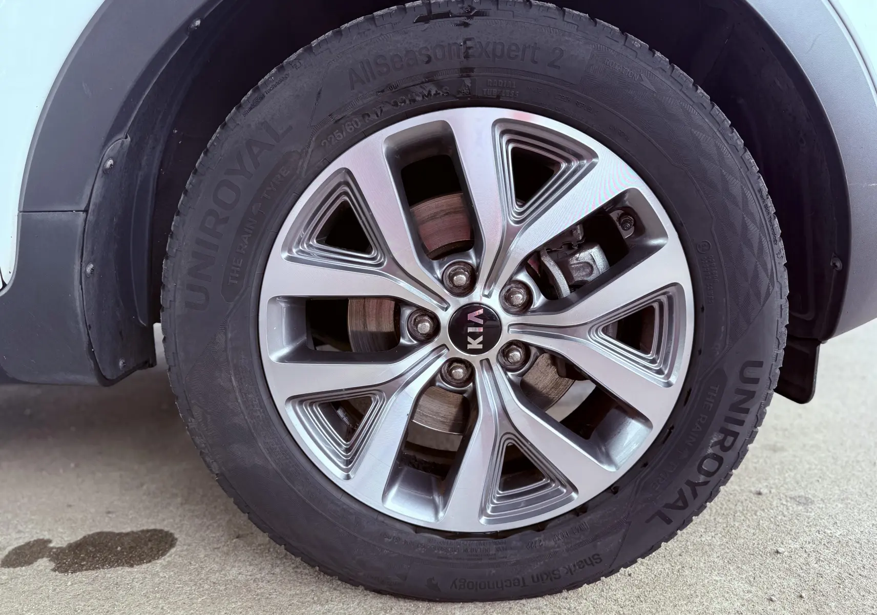 Gros plan sur la roue avant droite d'un KIA SPORTAGE blanche, mettant en valeur la jante alliage et le pneu Uniroyal.
