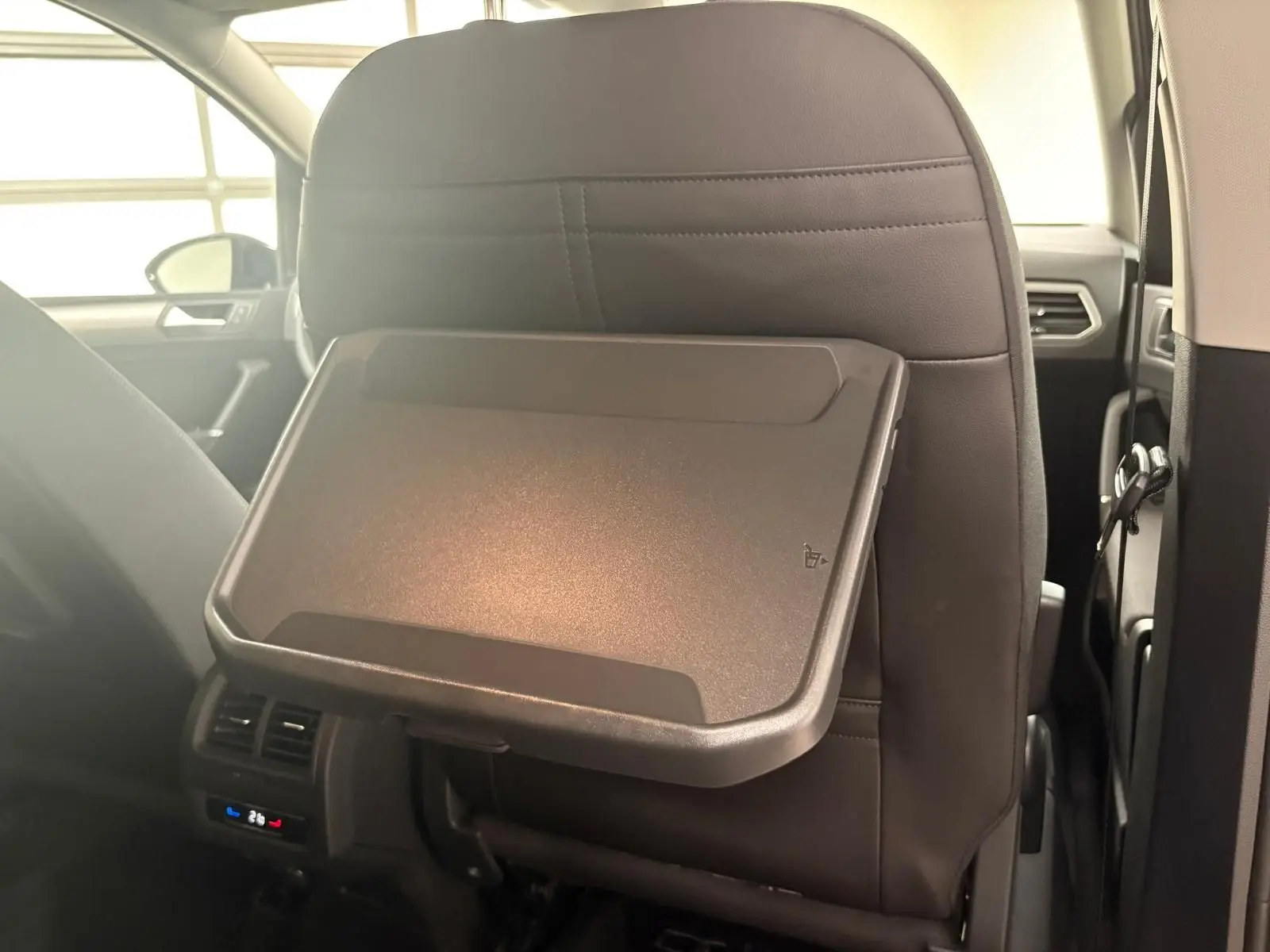 Tablette rabattable en plastique fixée au dossier du siège avant dans l'habitacle du Volkswagen Touran gris dauphin 2025.